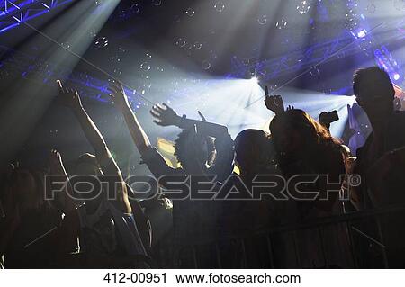 Crowd cheering with arms raised at concert View Large Photo Image Stock Image - Crowd cheering with arms raised at concert. Fotosearch