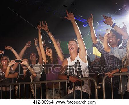 Enthusiastic crowd with arms raised behind railing at concert View Large Photo Image Picture - Enthusiastic crowd with arms raised behind railing at concert. Fotosearch