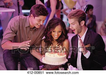 Stock Image - Friends with birthday cake in nightclub. Fotosearch