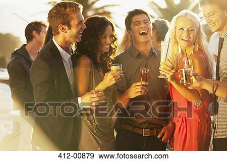 Laughing friends drinking cocktails on sunny balcony View Large Photo Image Stock Photo - Laughing friends drinking cocktails on sunny balcony. Fotosearch