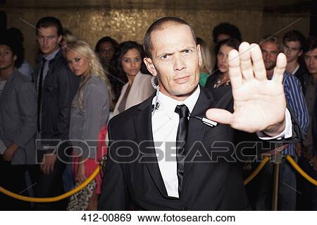 Stock Photo - Portrait of bouncer with arm outstretched outside nightclub. Fotosearch