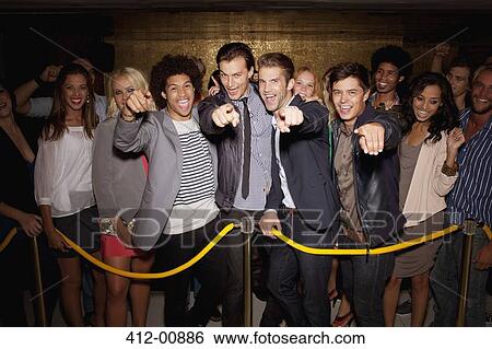 Stock Photograph - Portrait of enthusiastic crowd waiting in queue outside night club. Fotosearch