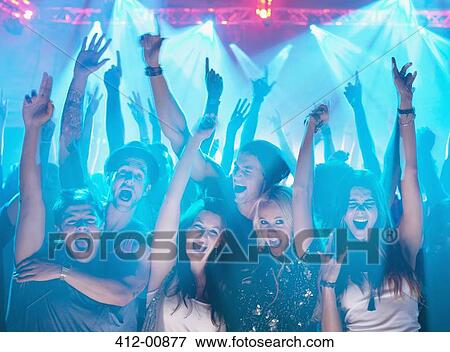 Stock Photo - Portrait of enthusiastic crowd with arms raised at concert. Fotosearch