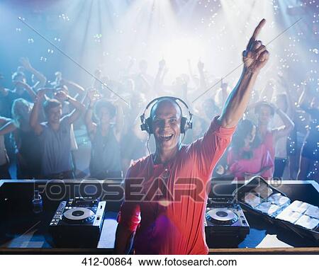 Portrait of enthusiastic DJ with arm raised and people on dance floor in background View Large Photo Image Picture - Portrait of enthusiastic DJ with arm raised and people on dance floor in background. Fotosearch