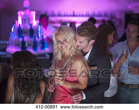 Stock Image - Portrait of smiling couple with cocktails in nightclub. Fotosearch