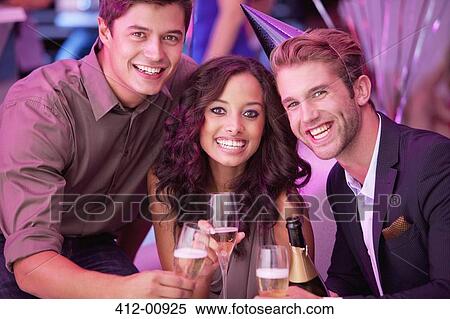 Stock Photography - Portrait of smiling friends drinking champagne in nightclub. Fotosearch