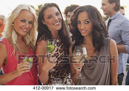 Stock Photo - Portrait of smiling women drinking cocktails. Fotosearch