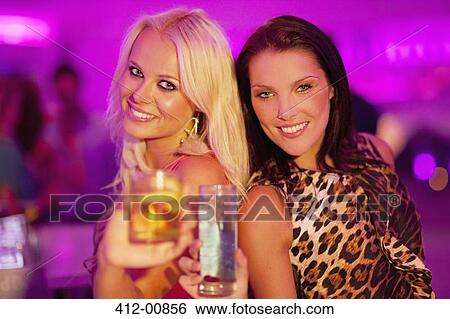 Portrait of smiling women toasting cocktails at nightclub View Large Photo Image Stock Photograph - Portrait of smiling women toasting cocktails at nightclub. Fotosearch