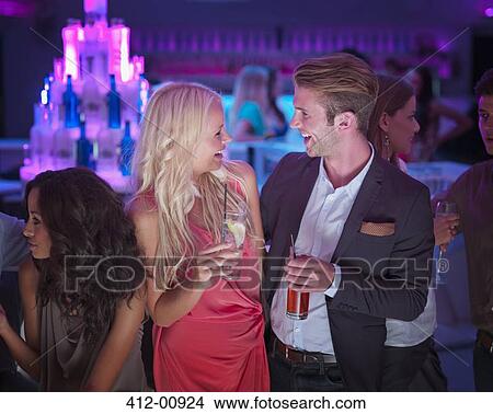 Picture - Smiling couple drinking cocktails in nightclub. Fotosearch