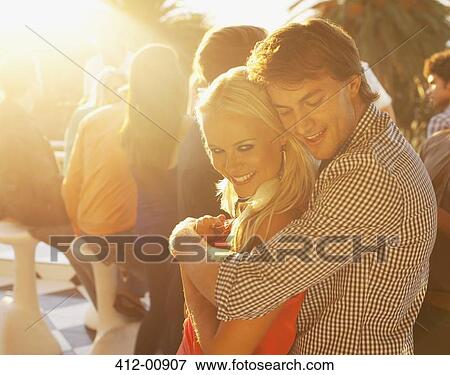 Stock Photo - Smiling couple hugging on sunny balcony. Fotosearch