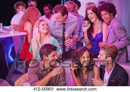 Stock Image - Smiling friends drinking champagne in nightclub. Fotosearch