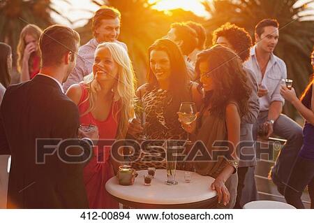 Smiling friends drinking cocktails on sunny balcony View Large Photo Image Picture - Smiling friends drinking cocktails on sunny balcony. Fotosearch