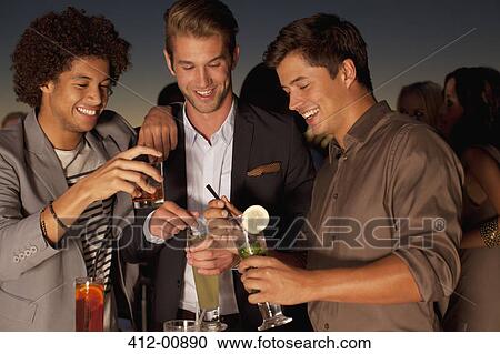 Smiling men toasting cocktails in nightclub View Large Photo Image Stock Image - Smiling men toasting cocktails in nightclub. Fotosearch