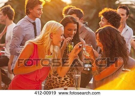Smiling women drinking cocktails on sunny balcony View Large Photo Image Stock Photo - Smiling women drinking cocktails on sunny balcony. Fotosearch