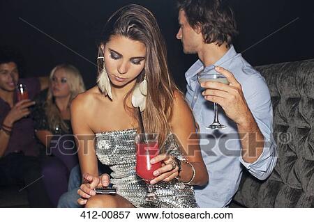 Woman with cocktail checking cell phone in nightclub View Large Photo Image Stock Photo - Woman with cocktail checking cell phone in nightclub. Fotosearch