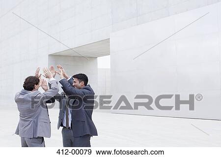 Business people high-fiving outside cultural center View Large Photo Image Stock Photo - Business people high-fiving outside cultural center. Fotosearch