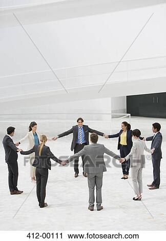 Stock Image - Business people holding hands in circle. Fotosearch