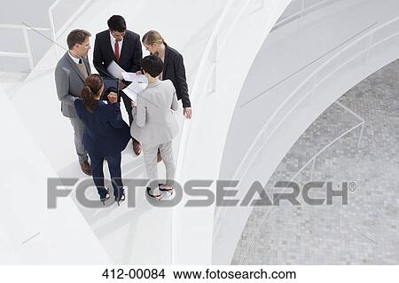 Picture - Business people reviewing paperwork on elevated walkway. Fotosearch