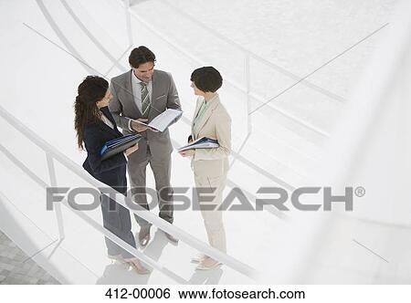 Business people reviewing paperwork on walkway View Large Photo Image Stock Photograph - Business people reviewing paperwork on walkway. Fotosearch