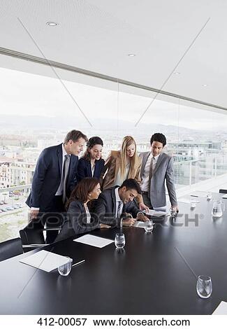 Business people watching businessman sign contract in conference room View Large Photo Image Stock Photo - Business people watching businessman sign contract in conference room. Fotosearch
