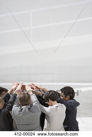 Picture - Business people with arms raised in huddle. Fotosearch