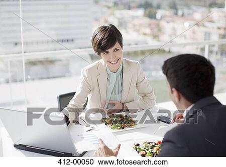 Stock Image - Businessman and businesswoman with laptop meeting over lunch. Fotosearch