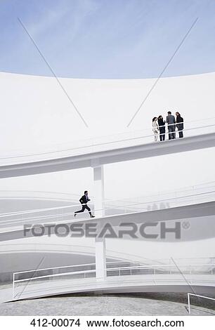 Businessman running up elevated walkway toward business people View Large Photo Image Picture - Businessman running up elevated walkway toward business people. Fotosearch