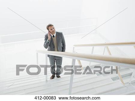 Businessman talking on cell phone at base of stairs View Large Photo Image Stock Image - Businessman talking on cell phone at base of stairs. Fotosearch