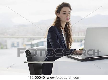 Stock Image - Businesswoman using laptop in office. Fotosearch