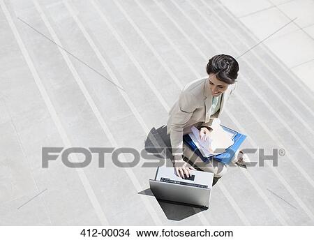 Businesswoman with paperwork using laptop on urban steps View Large Photo Image Picture - Businesswoman with paperwork using laptop on urban steps. Fotosearch