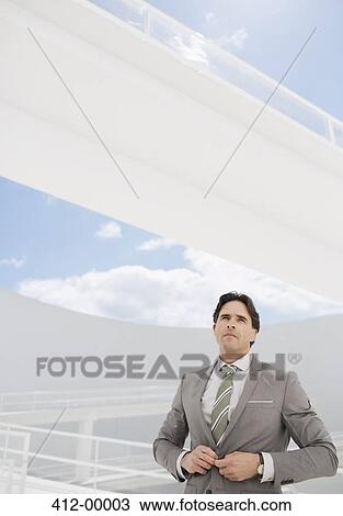 Stock Image - Confident businessman adjusting suit jacket. Fotosearch