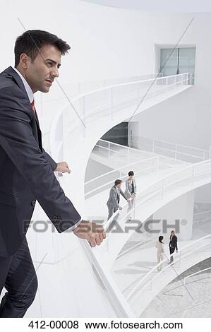 Pensive businessman leaning on railing of elevated walkway View Large Photo Image Stock Photo - Pensive businessman leaning on railing of elevated walkway. Fotosearch