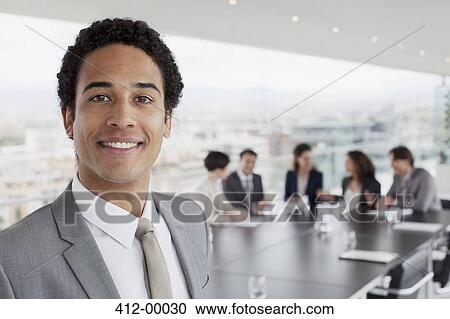 Stock Image - Portrait of smiling businessman in conference room. Fotosearch