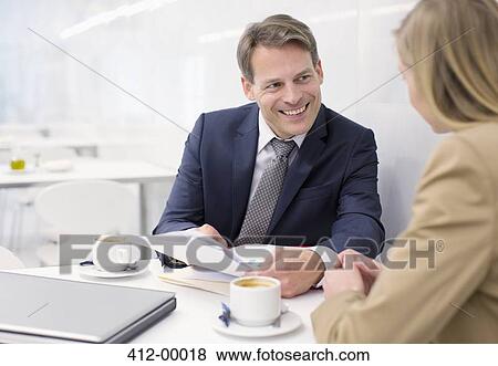 Smiling business people discussing paperwork in cafe View Large Photo Image Stock Photo - Smiling business people discussing paperwork in cafe. Fotosearch