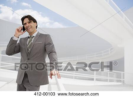 Stock Image - Smiling businessman talking on cell phone. Fotosearch