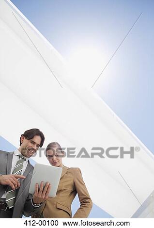 Sun shining over smiling businessman and businesswoman using digital tablet View Large Photo Image Stock Image - Sun shining over smiling businessman and businesswoman using digital tablet. Fotosearch