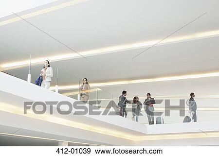 Business people leaning on glass railing of elevated walkway View Large Photo Image Stock Photo - Business people leaning on glass railing of elevated walkway. Fotosearch