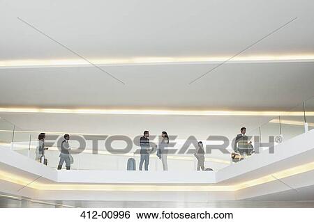Stock Photograph - Business people on elevated walkway in airport. Fotosearch