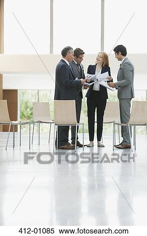 Stock Photography - Business people reviewing paperwork in lobby. Fotosearch