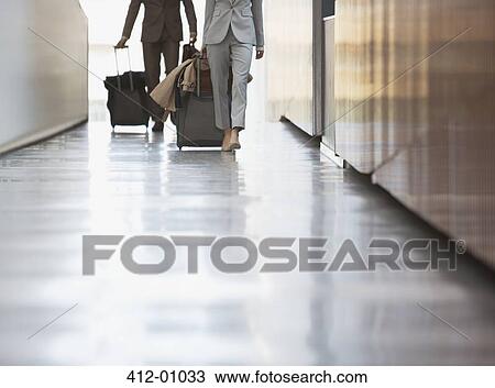 Businessman and businesswoman pulling suitcase down ramp in airport View Large Photo Image Stock Image - Businessman and businesswoman pulling suitcase down ramp in airport. Fotosearch