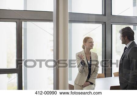 Stock Image - Businessman and businesswoman talking in conference room. Fotosearch