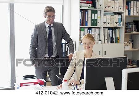 Businessman and businesswoman using computer at desk in office View Large Photo Image Stock Image - Businessman and businesswoman using computer at desk in office. Fotosearch