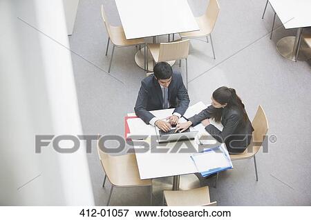 Stock Photo - Businessman and businesswoman working on laptop at cafe. Fotosearch