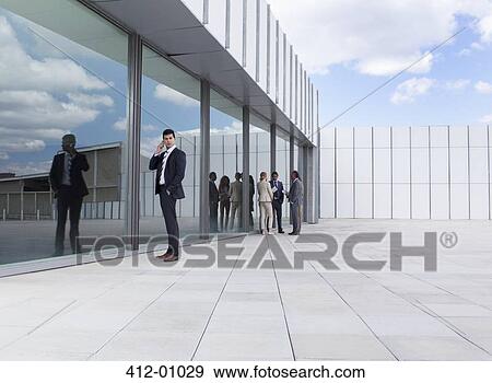 Businessman talking on cell phone outside building View Large Photo Image Stock Photo - Businessman talking on cell phone outside building. Fotosearch