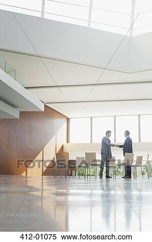 Businessmen shaking hands at circle of chairs in lobby View Large Photo Image Stock Photography - Businessmen shaking hands at circle of chairs in lobby. Fotosearch