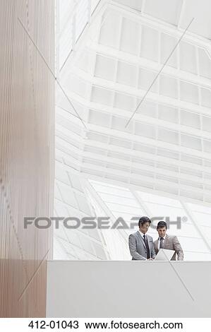 Businessmen using laptop in modern office View Large Photo Image Stock Image - Businessmen using laptop in modern office. Fotosearch