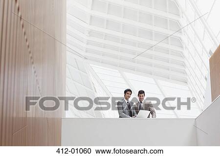 Businessmen using laptop in modern office View Large Photo Image Stock Image - Businessmen using laptop in modern office. Fotosearch