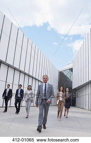 Stock Photography - Confident business people walking outside building. Fotosearch