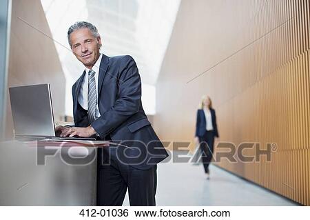 Portrait of confident businessman using laptop in office View Large Photo Image Stock Photograph - Portrait of confident businessman using laptop in office. Fotosearch