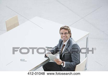 Portrait of confident businessman with digital tablet at table View Large Photo Image Stock Photo - Portrait of confident businessman with digital tablet at table. Fotosearch